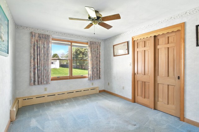 unfurnished bedroom featuring a baseboard radiator, carpet flooring, baseboards, and a closet