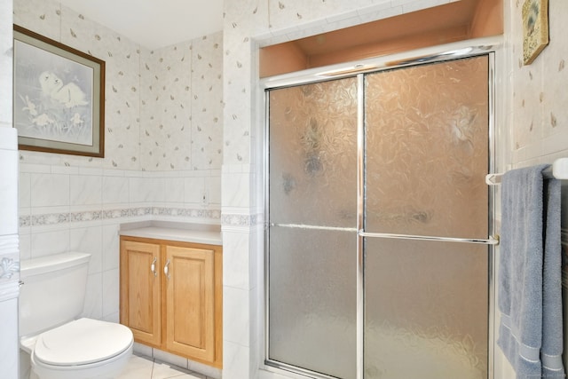full bath with wallpapered walls, a shower stall, tile walls, wainscoting, and toilet