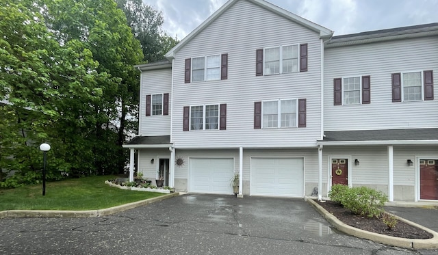 townhome / multi-family property featuring a front yard, a garage, and aphalt driveway