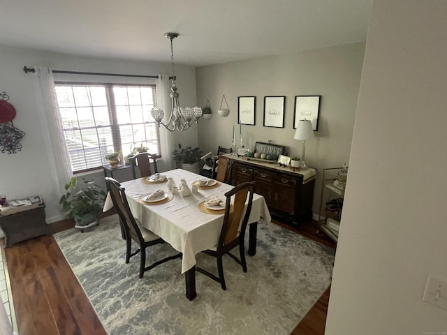 dining space with an inviting chandelier, baseboards, and wood finished floors