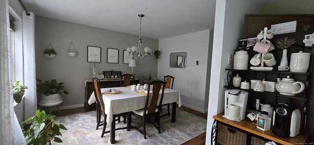 dining area with baseboards, an inviting chandelier, and wood finished floors
