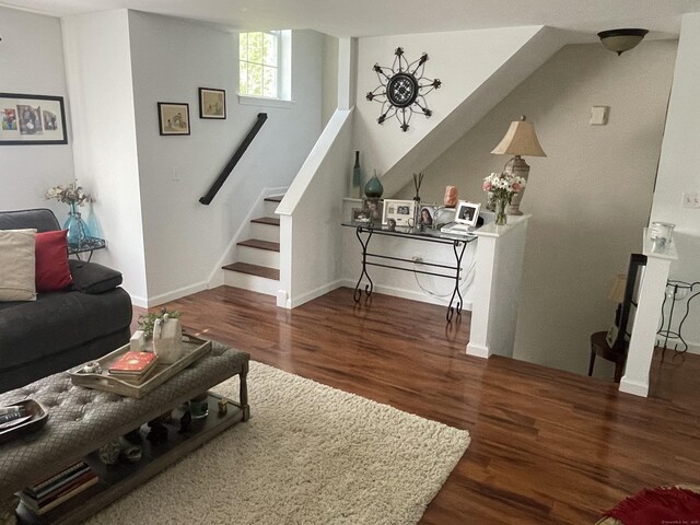 living area with wood finished floors, baseboards, and stairs