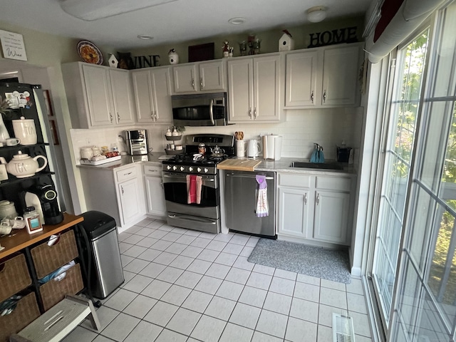 kitchen with a sink, tasteful backsplash, white cabinets, and appliances with stainless steel finishes