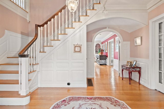 44 Walbridge Rd, West Hartford, CT 06119 - entryway with a decorative wall, arched walkways, light wood-style floors, stairs, and a wainscoted wall