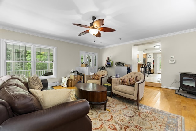 18 Brookside Trl, Monroe, CT 06468 - living area featuring a baseboard radiator, a wood stove, crown molding, ceiling fan, and light wood-style flooring