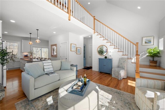 living area featuring recessed lighting, wood finished floors, a towering ceiling, and stairs