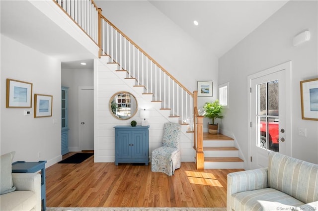 interior space with high vaulted ceiling, wood finished floors, baseboards, and stairs