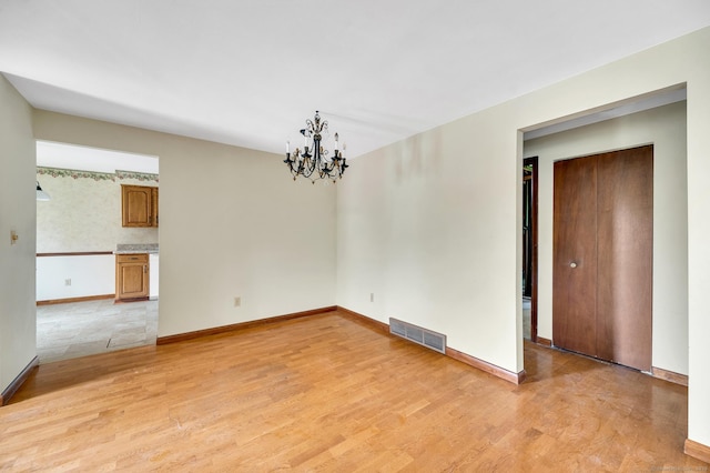 unfurnished dining area featuring a chandelier, baseboards, light wood-type flooring, and visible vents