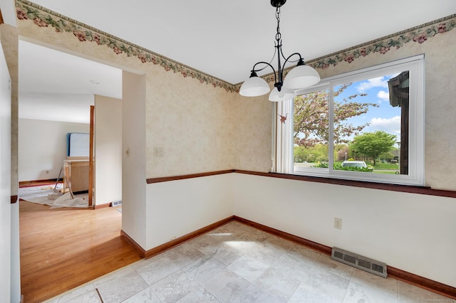 unfurnished dining area featuring visible vents, baseboards, and a notable chandelier