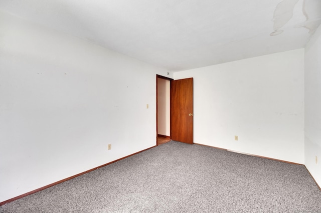 unfurnished room featuring carpet and baseboards