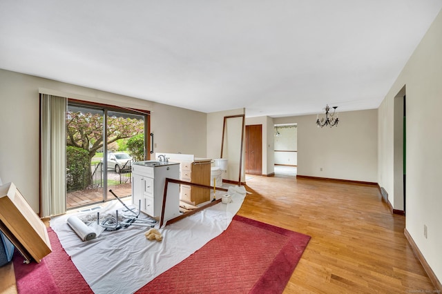 interior space with baseboards, a notable chandelier, and light wood finished floors