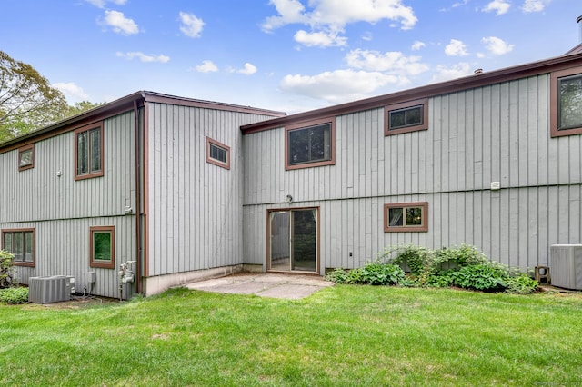 back of property featuring central air condition unit and a lawn