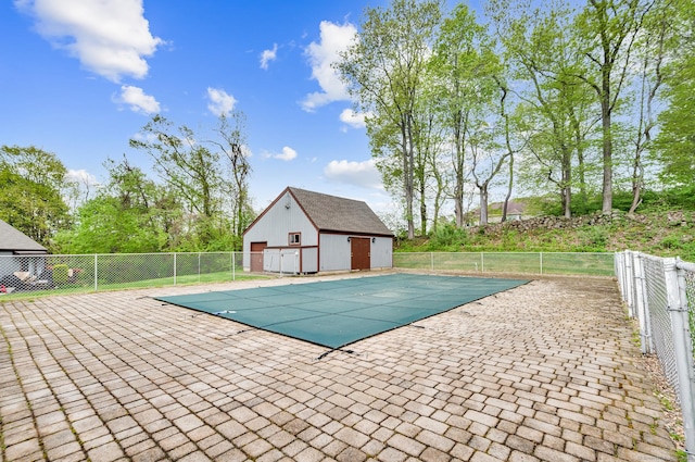 view of swimming pool with a patio area, a fenced in pool, fence, and an outbuilding
