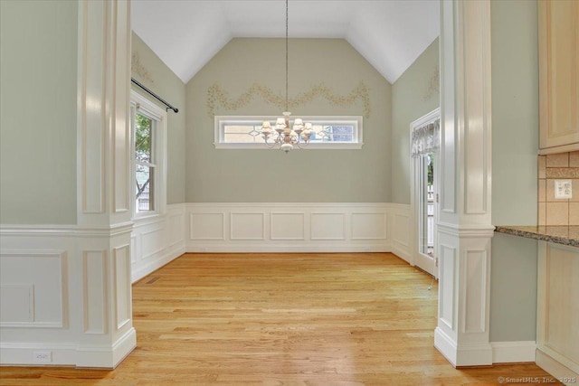 unfurnished dining area featuring vaulted ceiling, a notable chandelier, and light wood-style floors