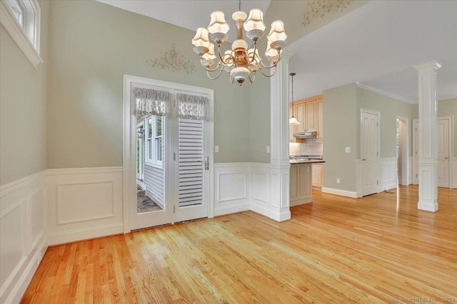 unfurnished dining area with a decorative wall, a wealth of natural light, light wood-style flooring, and decorative columns