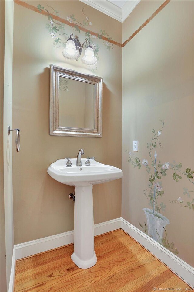 bathroom featuring crown molding, baseboards, and wood finished floors