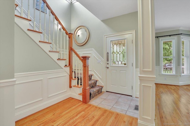 foyer featuring wood finished floors, visible vents, a decorative wall, wainscoting, and stairs