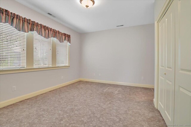 unfurnished bedroom featuring baseboards, a closet, visible vents, and carpet