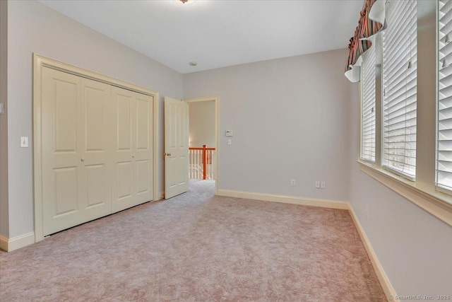 unfurnished bedroom featuring baseboards, carpet flooring, and a closet