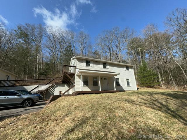 view of front of house with a porch, stairs, and a front yard