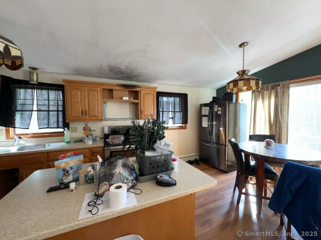 kitchen featuring brown cabinets, a sink, open shelves, stainless steel appliances, and light countertops
