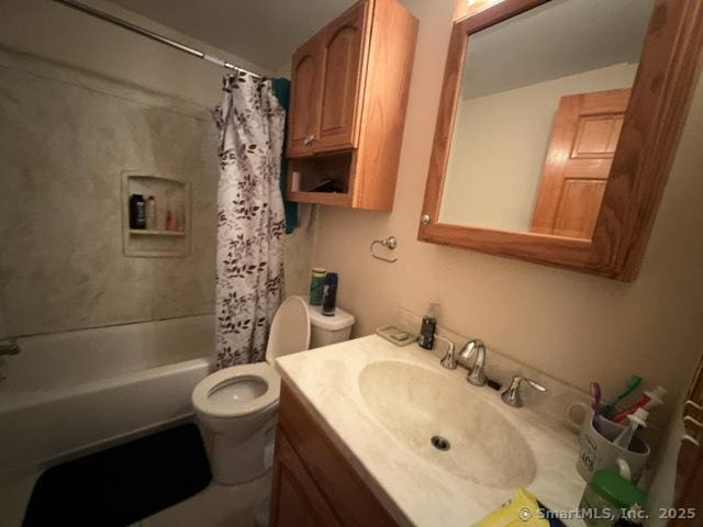 full bath featuring toilet, vanity, and shower / bath combo with shower curtain