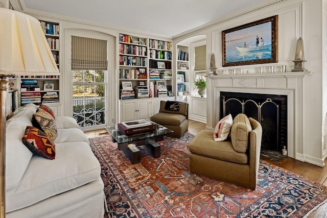 3113 Bronson Rd, Fairfield, CT 06824 - living room featuring wood finished floors, a fireplace, built in shelves, and ornamental molding