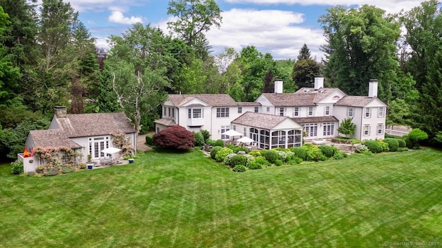 3113 Bronson Rd, Fairfield, CT 06824 - rear view of house featuring a sunroom, a chimney, a lawn, and an outdoor structure