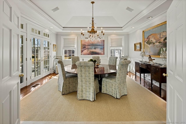 3113 Bronson Rd, Fairfield, CT 06824 - dining space with a chandelier, french doors, wood finished floors, a tray ceiling, and a decorative wall
