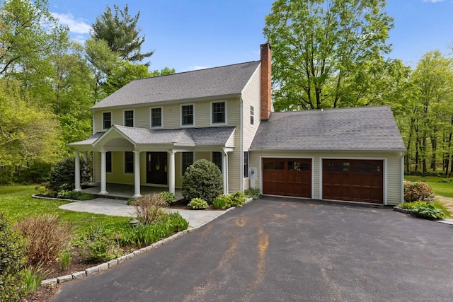 9 Brick School Dr, Redding, CT 06896 - view of front of house with a porch, an attached garage, a chimney, asphalt driveway, and roof with shingles