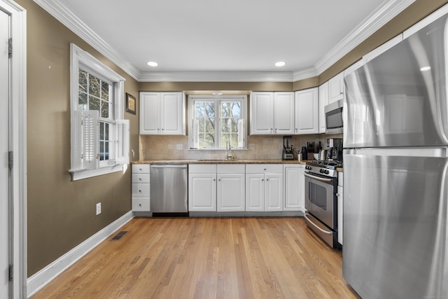 kitchen with a sink, stainless steel appliances, visible vents, light wood finished floors, and white cabinetry