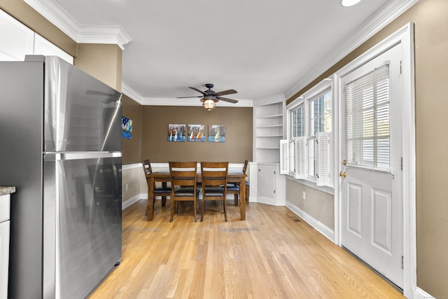 dining area with crown molding, baseboards, light wood-type flooring, and a ceiling fan