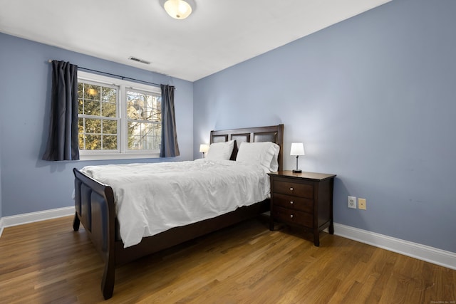 bedroom featuring baseboards, visible vents, and wood finished floors