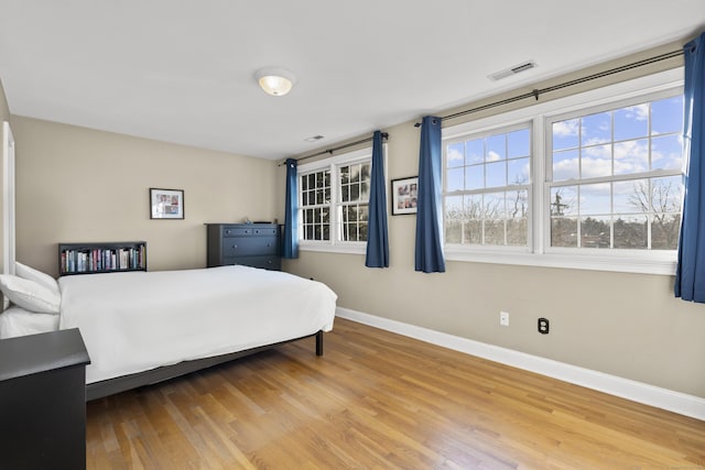 bedroom featuring baseboards, visible vents, and wood finished floors