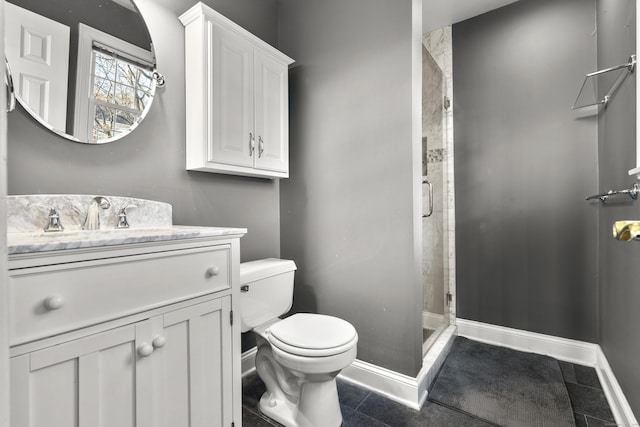 bathroom with vanity, toilet, baseboards, and a stall shower
