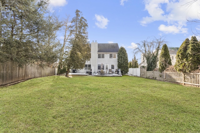 rear view of property with a chimney, a lawn, and a fenced backyard