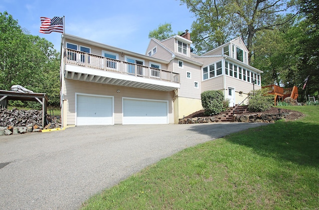 231 Lake Shore Dr, East Haddam, CT 06415 - view of front of house with driveway, a chimney, a garage, a front lawn, and a balcony