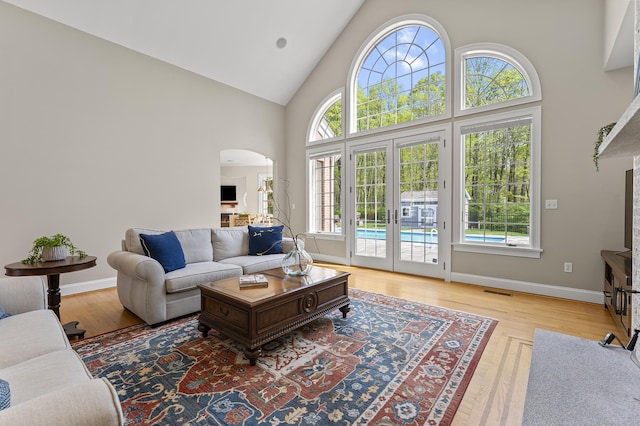 15 Hickory Hill Rd, Avon, CT 06001 - living room featuring french doors, high vaulted ceiling, baseboards, arched walkways, and light wood-style floors