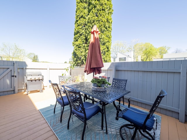 wooden terrace with a fenced backyard, area for grilling, a gate, and outdoor dining space