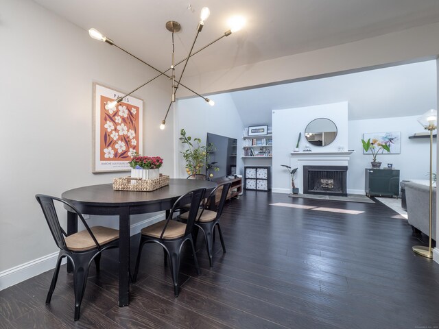 dining space featuring wood finished floors, baseboards, and a fireplace
