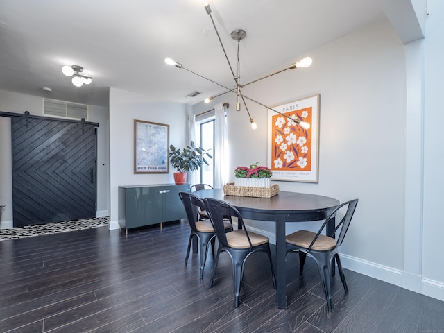 dining room with wood finished floors, visible vents, a barn door, and baseboards