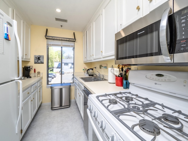 kitchen with a sink, white cabinets, visible vents, white appliances, and light countertops