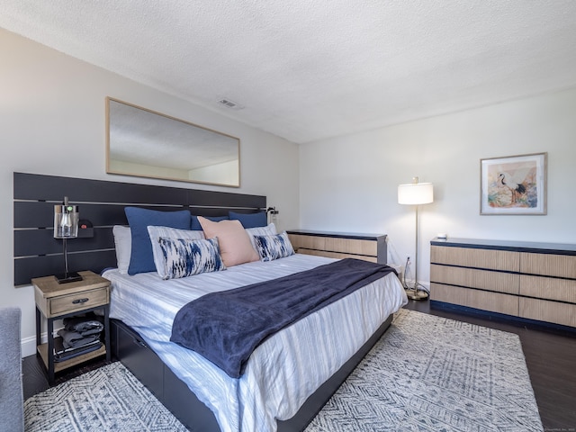 bedroom featuring visible vents, a textured ceiling, and wood finished floors