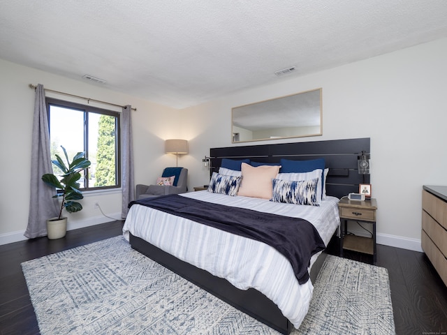 bedroom with dark wood finished floors, visible vents, baseboards, and a textured ceiling