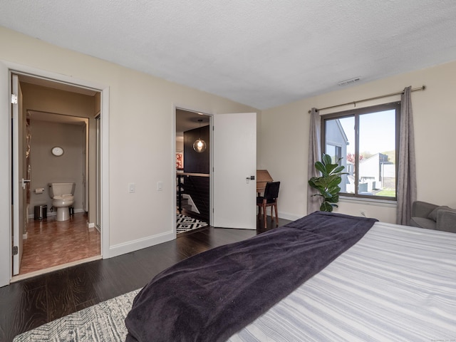 bedroom featuring a textured ceiling, visible vents, wood finished floors, and baseboards