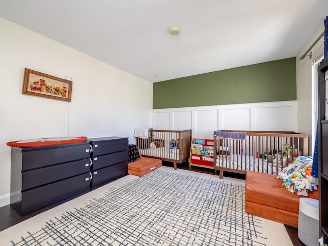 bedroom with wainscoting and a decorative wall