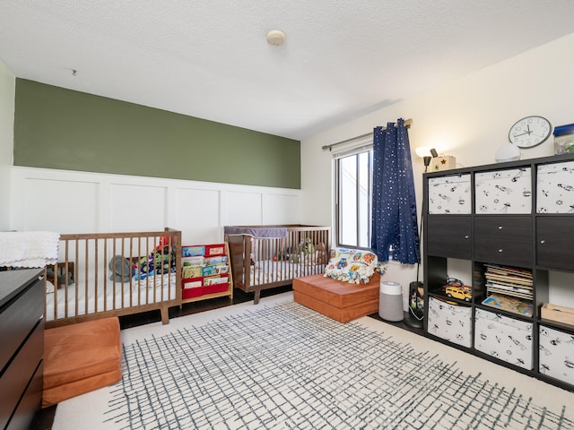 bedroom featuring carpet flooring, a decorative wall, and wainscoting