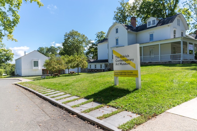exterior space featuring a chimney, a gambrel roof, and a front lawn