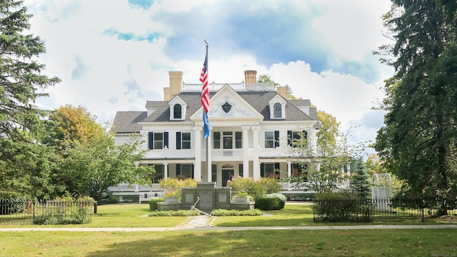 greek revival house with fence, a front lawn, and a chimney