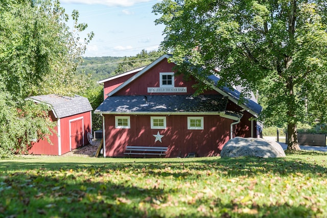 back of property with an outdoor structure, central AC unit, a lawn, and a storage unit